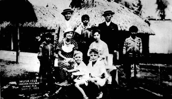 Family of tourists posed with Seminole Indians and a stuffed alligator